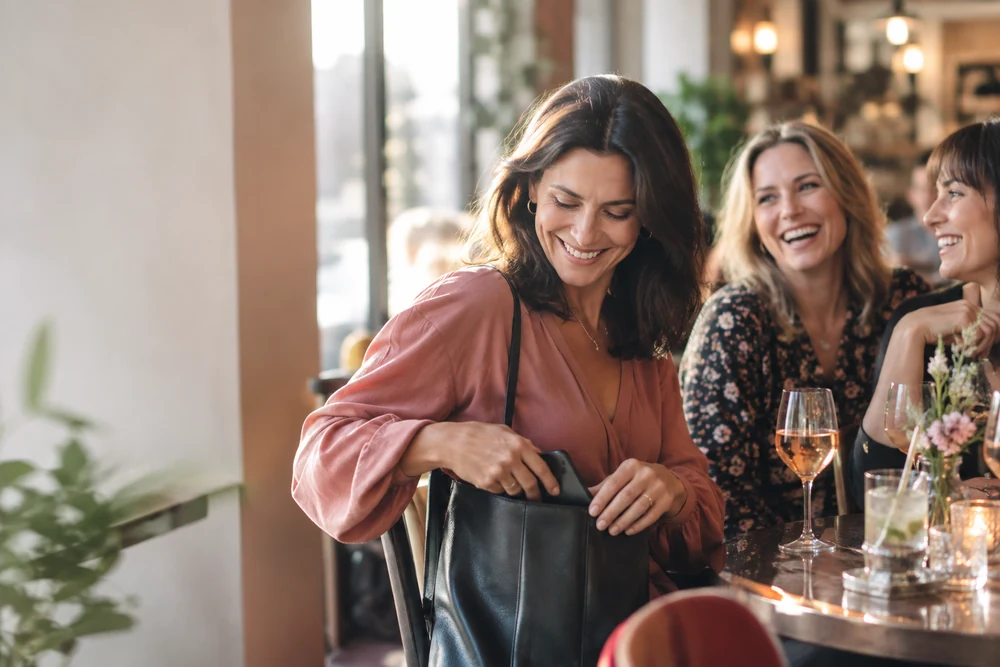 Réagir au ghosting : une femme range son téléphone et sort avec des amies, rires, lumière de soirée