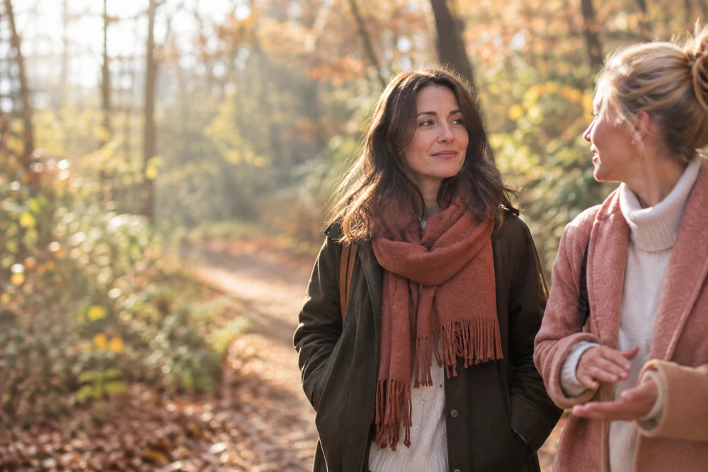 Il m'ignore : une femme se promène avec une amie en forêt, conversation détendue, lumière d'automne