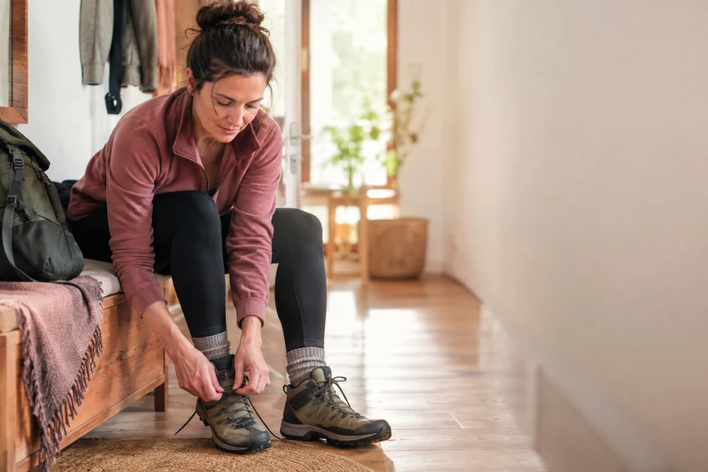 Ce qui reste possible : une femme lace ses chaussures de marche à l'entrée de son appartement