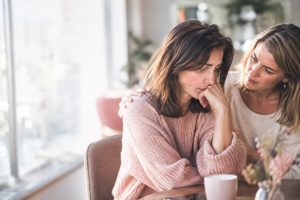 Relation toxique ou violente : une femme parle à une amie qui la soutient, main posée sur son épaule