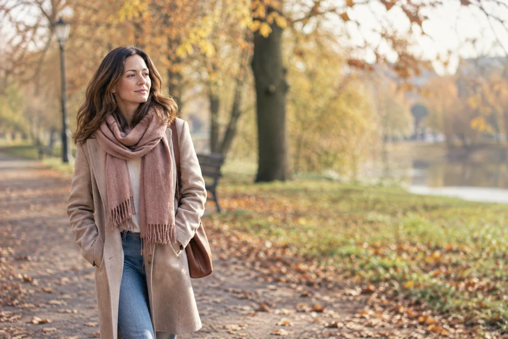 Récupérer son ex sans courir après lui : une femme marche seule dans un parc en automne, pas assuré, visage apaisé