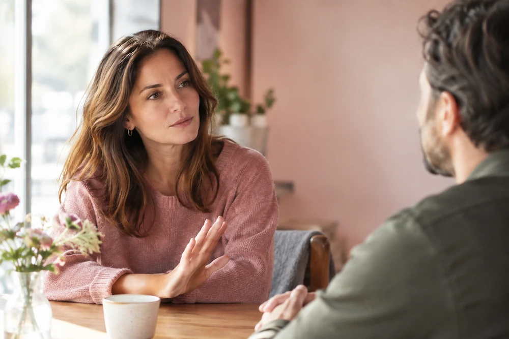 Estime de soi : une femme pose ses limites avec calme lors d'une conversation assise face à un homme, ambiance sereine